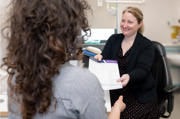 GP Lucy Dormer handing a form to a patient