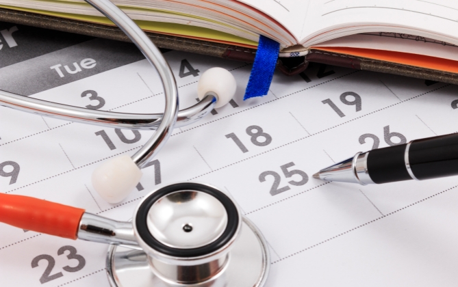 Calendar with stethoscope, book, and pen.